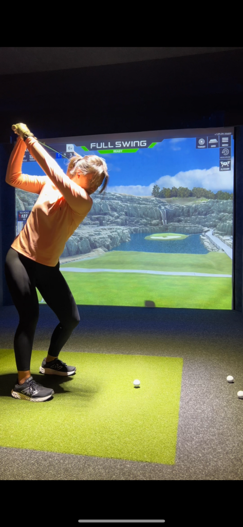 Golfer swinging in a One Swing Away simulator bay