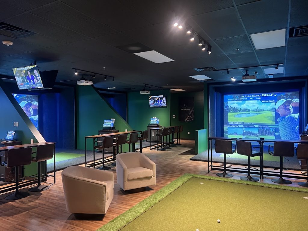 Wide interior view of the simulator bays, chairs, and putting area