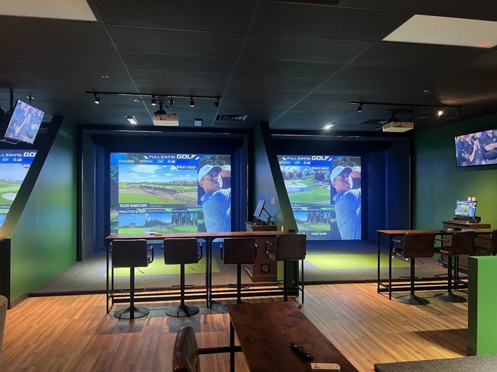 Tables and seating beside the indoor golf simulator bays